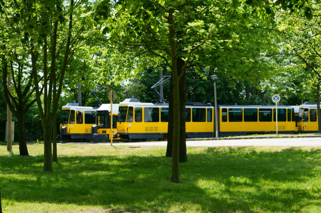 Zwei sonnengelbe historische Bahnen flankieren eine Straßenbahn des Typ GT6N. Sie stehen in der Gleisschleife Riesaer Straße